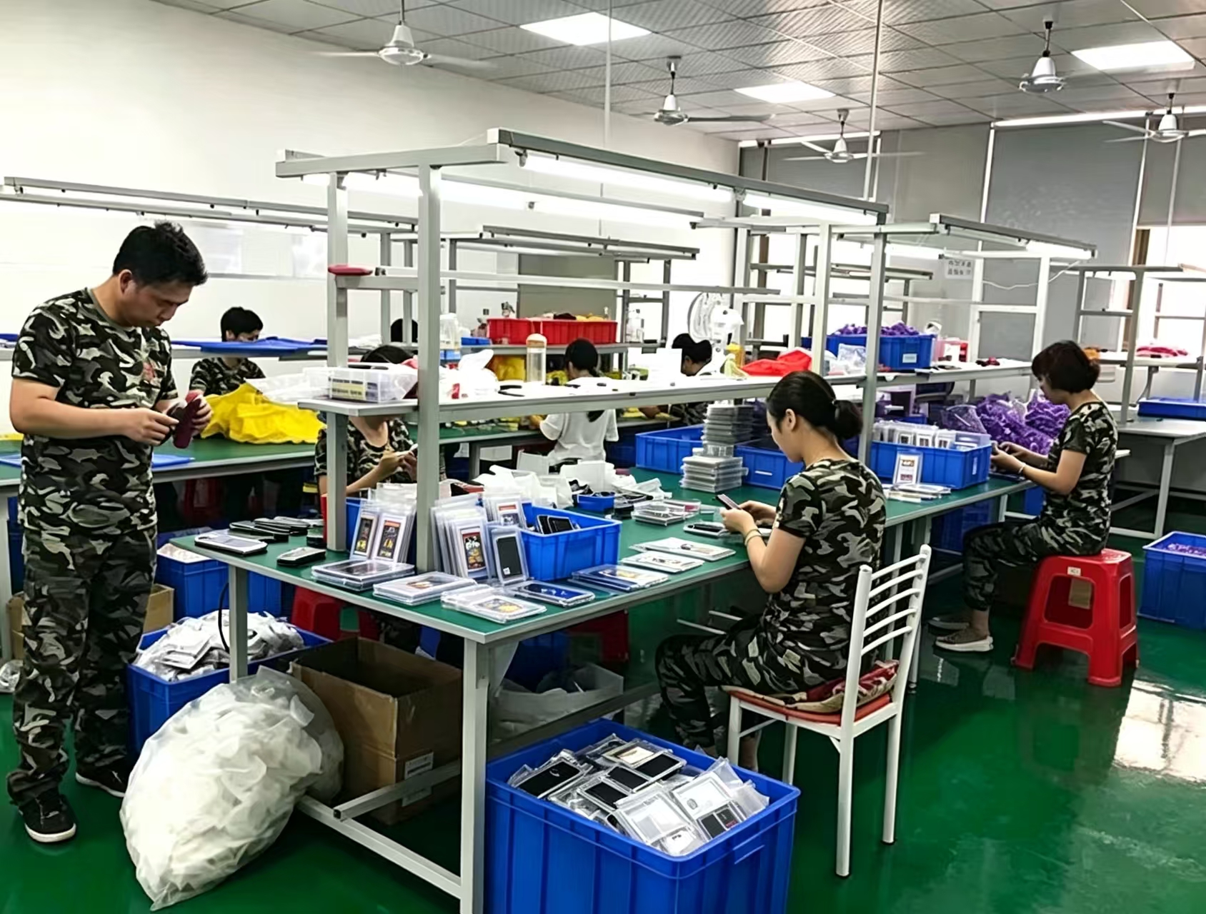 Assembly production line in Dongguan factory, workers assembling phone cases and trading card accessories, quality inspection for bulk wholesale orders