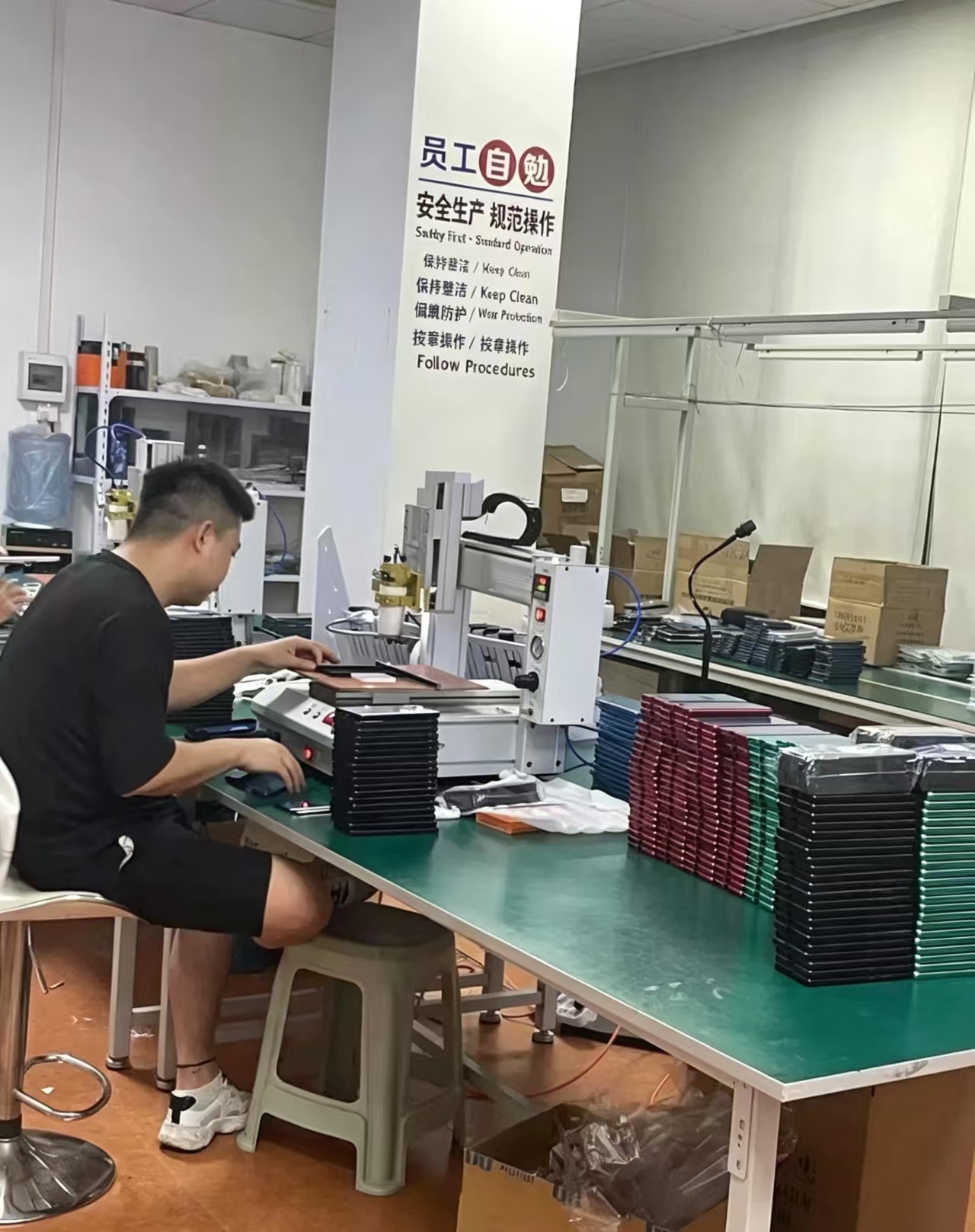 Quality‑control inspection workstation in Dongguan factory, worker checking finished PSA card holders and phone cases before shipment